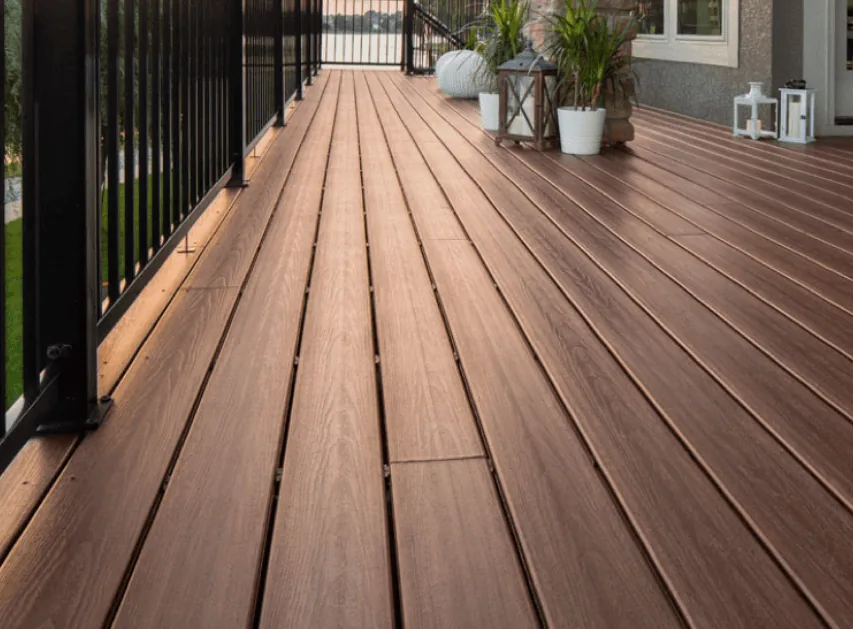 Close-up of brown composite decking boards with hidden fasteners, black metal railing and planters