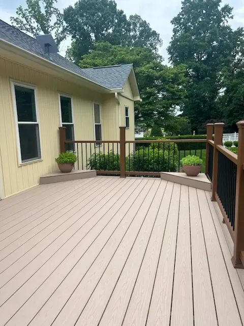 Tan composite deck with a curved corner, brown posts and black metal balusters