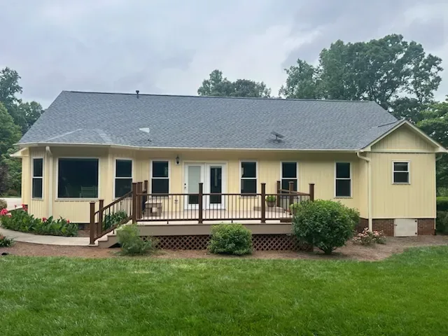 Wraparound low deck with railing and planting beds along the back of a ranch home
